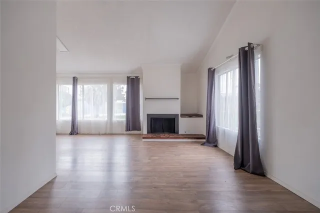 an empty room with windows and fireplace