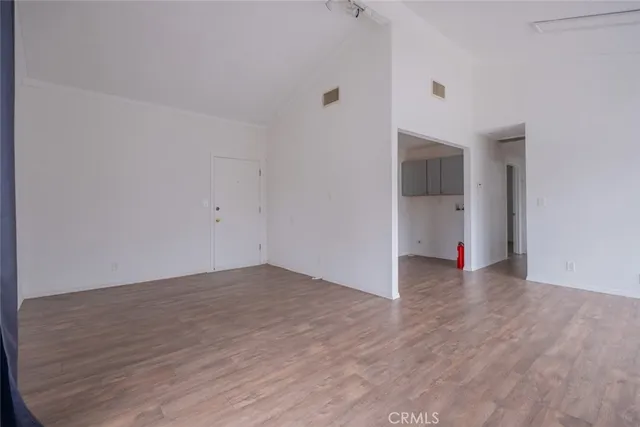 a view of an empty room with wooden floor and closet