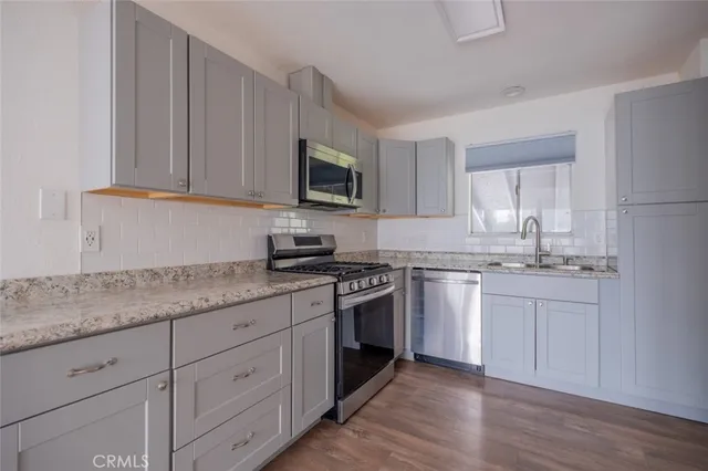 a kitchen with granite countertop white cabinets sink and stainless steel appliances