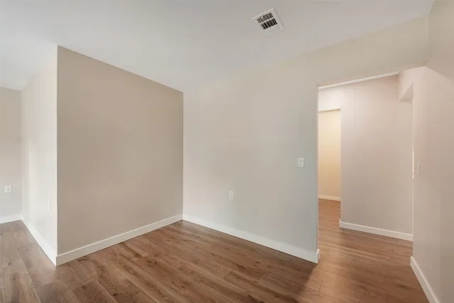 a view of an empty room with wooden floor and closet