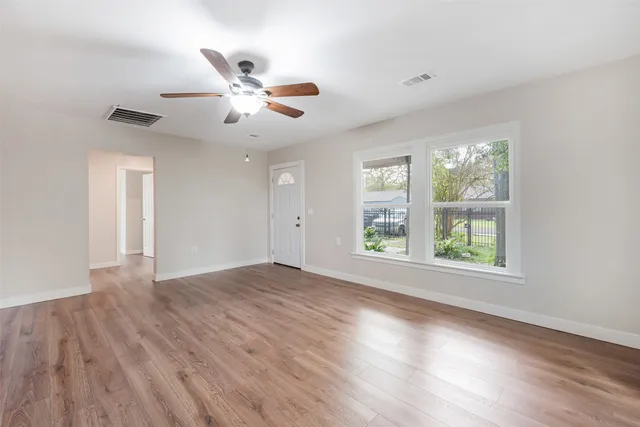 a view of an empty room with wooden floor and a window