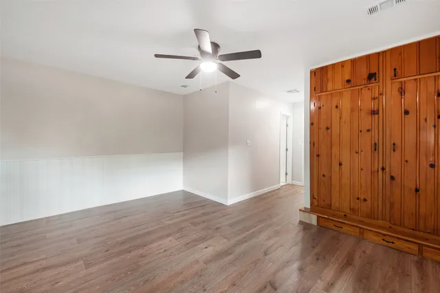 an empty room with wooden floor closet and windows