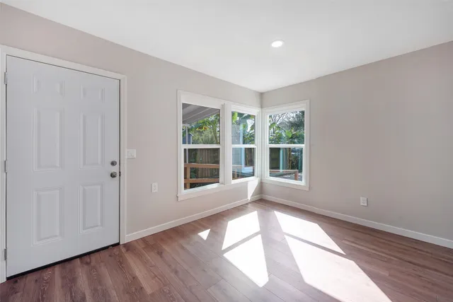 a view of an empty room with wooden floor and a window