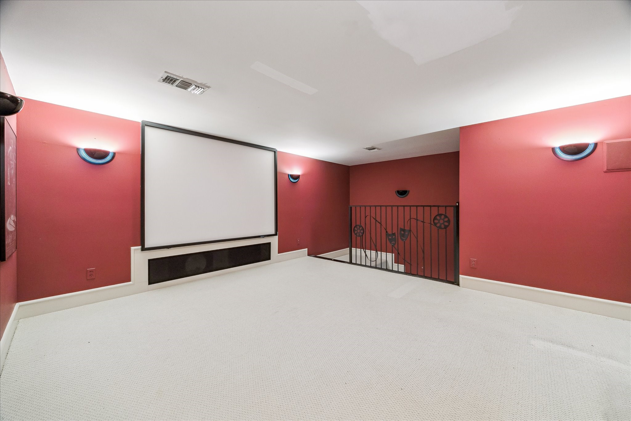 608 Little John Lane Houston, TX 77024 - Photo 33 of 46 The media room, with its custom iron banister, designer sconce lighting, and neutral carpet flooring, is the perfect space for movie nights and cozy entertainment.