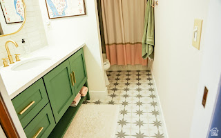 578 High Bench Road Alpine, UT 84004 - Photo 26 of 39 Bathroom featuring a green vanity with brass hardware, a white countertop, and an undermount sink with a brass faucet