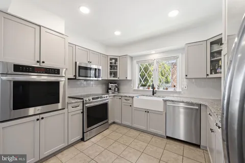 a kitchen with stainless steel appliances granite countertop white cabinets a sink dishwasher a stove and a refrigerator with wooden floor