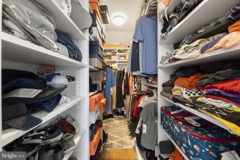 a view of walk in closet with clothes and shoes