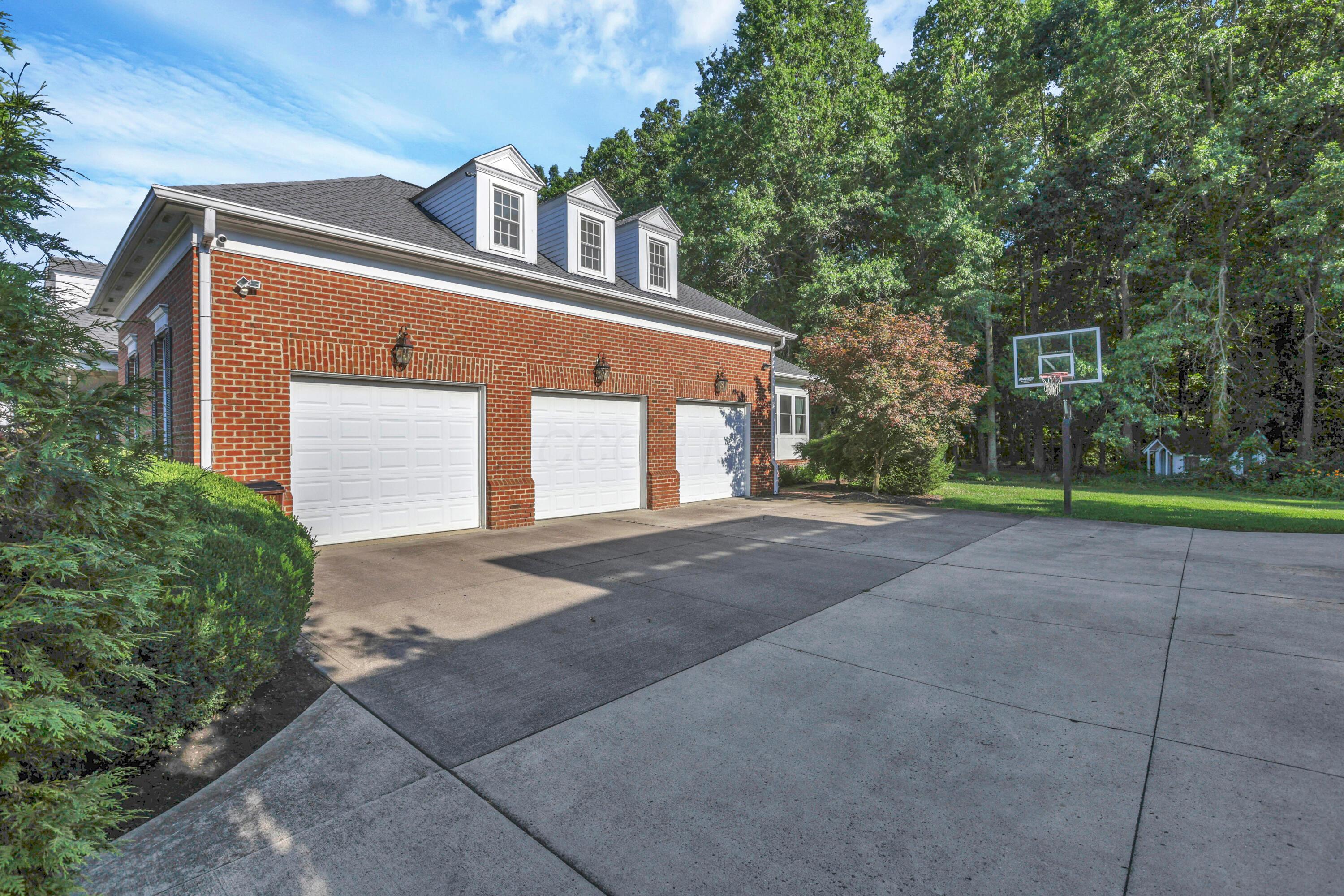 3575 State Rte 37 West Delaware, OH 43015 - Photo 14 of 106 Brick exterior featuring three white garage doors, dormer windows, and exterior lighting fixtures