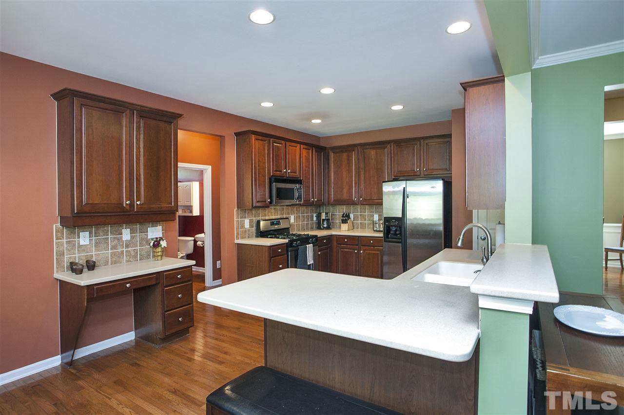 8621 Benzinger Drive Raleigh, NC 27613 - Photo 8 of 25 a kitchen with a sink a kitchen island wooden floors and stainless steel appliances