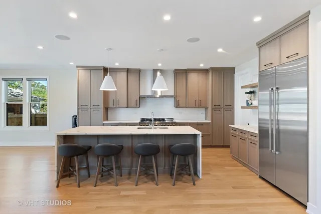 a kitchen with stainless steel appliances granite countertop a table chairs sink refrigerator and cabinets