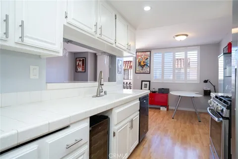 a kitchen with a sink dishwasher a dining table and chairs with wooden floor
