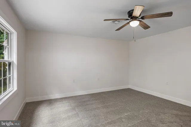 an empty room with a window and a fan