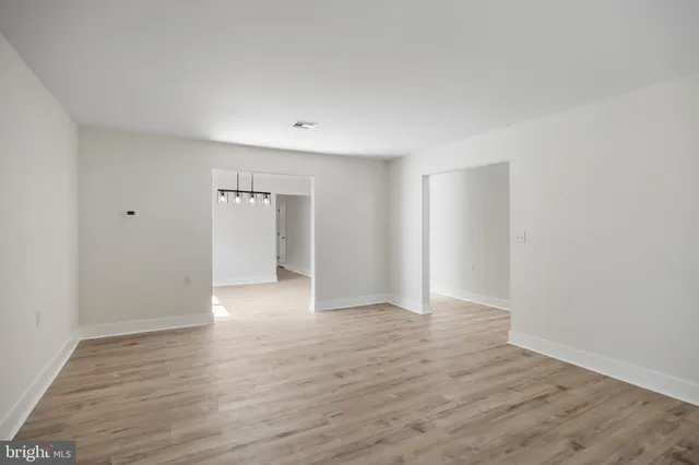 a view of an empty room with wooden floor and closet