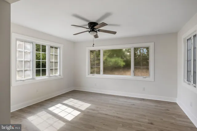 a view of an empty room with a window and wooden floor