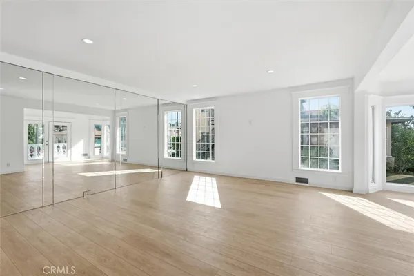 a view of an empty room with window and wooden floor