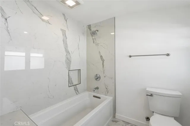 a bathroom with a bathtub shower and toilet
