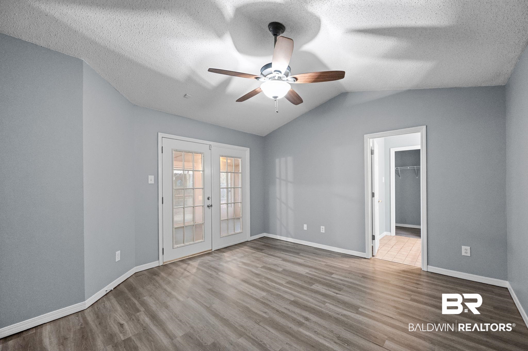 3744 Pepper Ridge Drive Mobile, AL 36693 - Photo 13 of 29 Empty room featuring french doors, vaulted ceiling, wood finished floors, a textured ceiling, and a ceiling fan