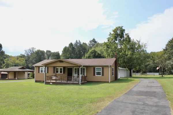 a front view of a house with yard porch and a tree