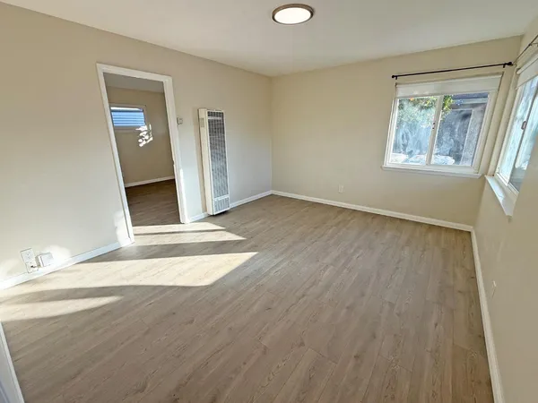 a view of an empty room with wooden floor and a window