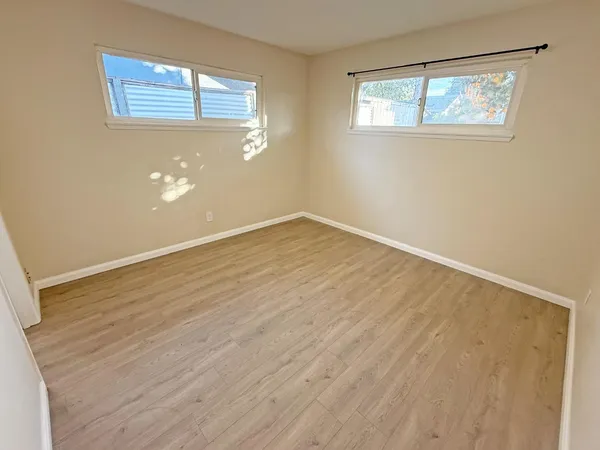 a view of an empty room with wooden floor and a window