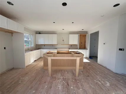 a large white kitchen with a sink and a refrigerator