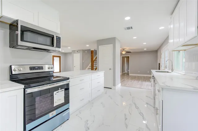 a kitchen with stainless steel appliances kitchen island granite countertop a stove a sink and a microwave