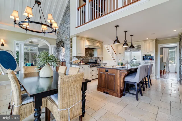 a kitchen with stainless steel appliances a dining table chairs stove and cabinets