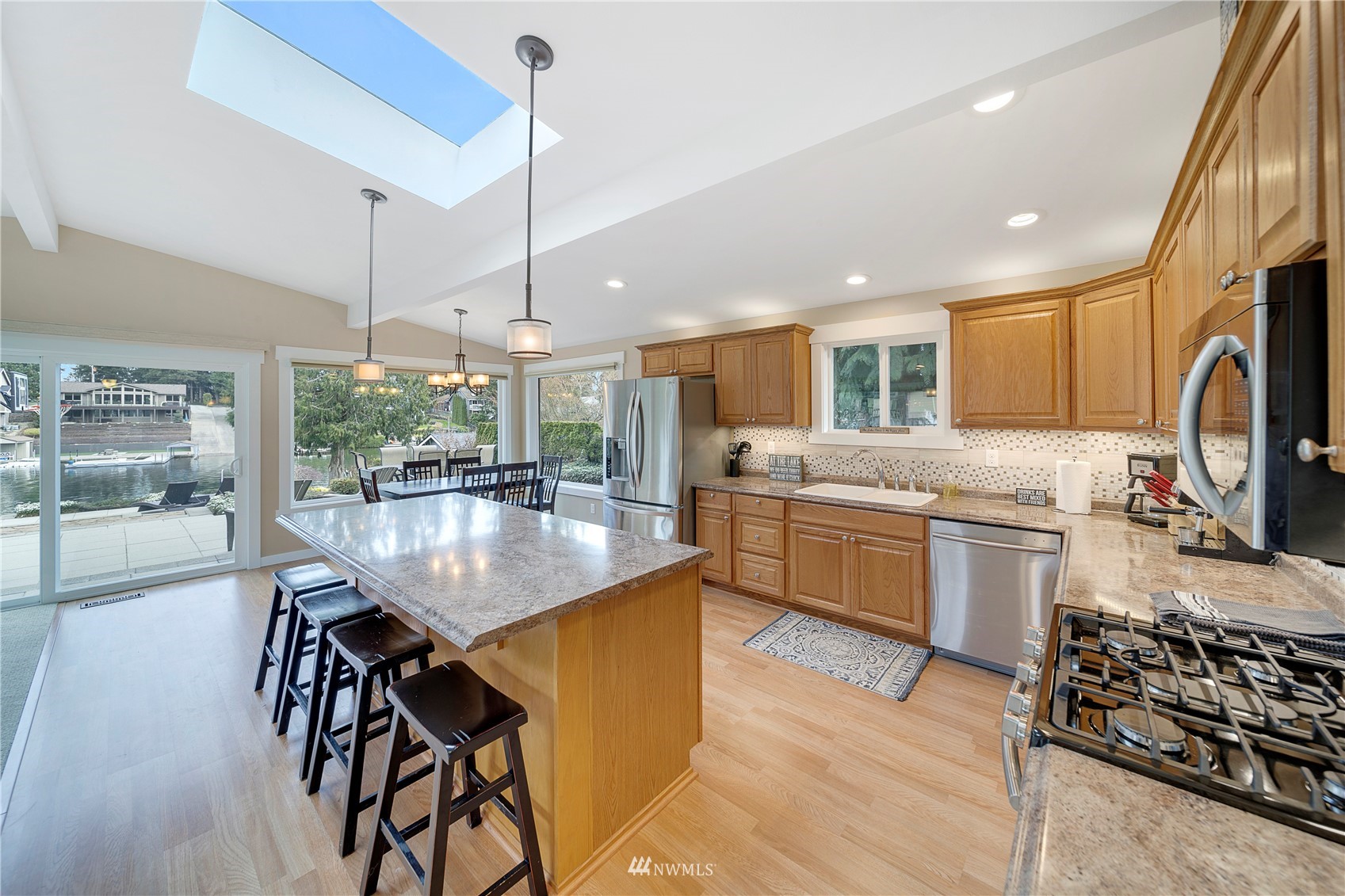 1919 Channel Road East Lake Tapps, WA 98391 - Photo 7 of 33 a kitchen with stainless steel appliances kitchen island granite countertop a stove top oven a sink a dining table and chairs with wooden floor