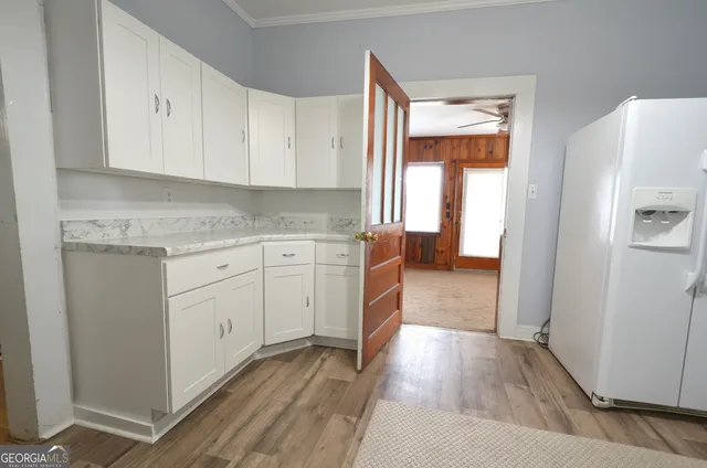a kitchen with white cabinets and wooden floor