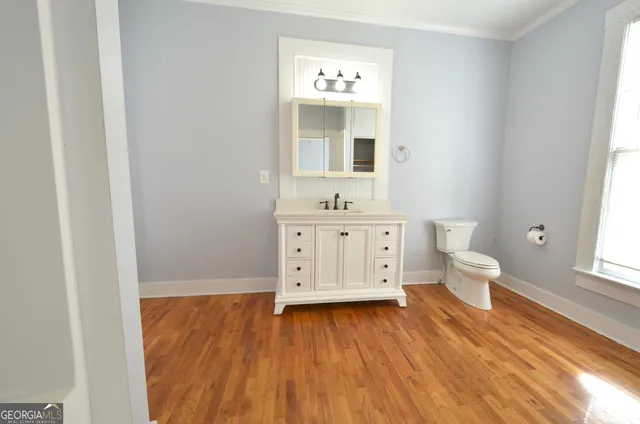 a view of a bathroom with toilet window and wooden floor