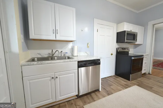 a kitchen with stainless steel appliances granite countertop a refrigerator sink and white cabinets