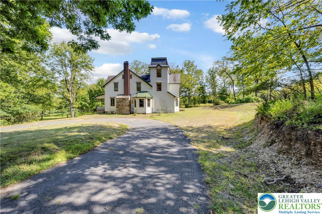384 Henry Road Nazareth, PA 18064 - Photo 20 of 54 A paved driveway leads toward a classic multi-level residence nestled among mature shade trees.