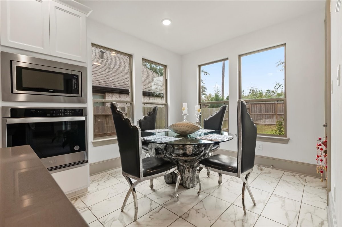 712 Fall Rock Branch Drive Conroe, TX 77304 - Photo 7 of 23 a dining room with furniture a fireplace wooden floor and a rug