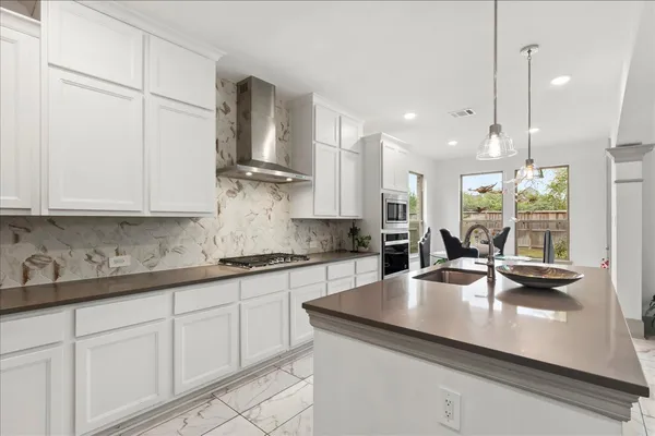 a kitchen with stainless steel appliances granite countertop a sink a stove and white cabinets with wooden floor