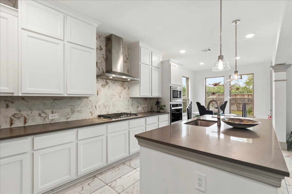 712 Fall Rock Branch Drive Conroe, TX 77304 - Photo 9 of 23 a kitchen with stainless steel appliances granite countertop a sink a stove and white cabinets with wooden floor
