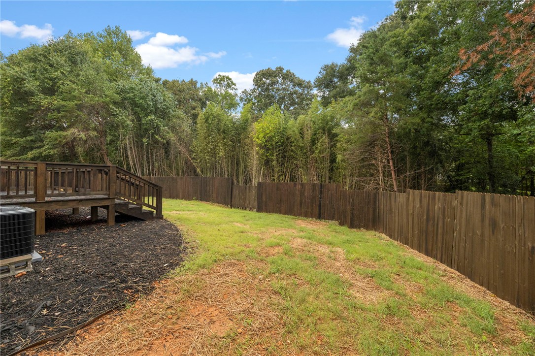 474 Bryant Road Pelzer, SC 29669 - Photo 43 of 44 Mature trees frame a spacious grassy backyard bordered by a privacy fence.