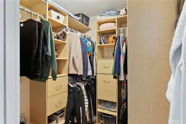 a view of walk in closet with clothes and shoes
