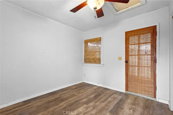 an empty room with wooden floor chandelier fan and windows