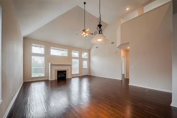 a view of an empty room with wooden floor fireplace and a window