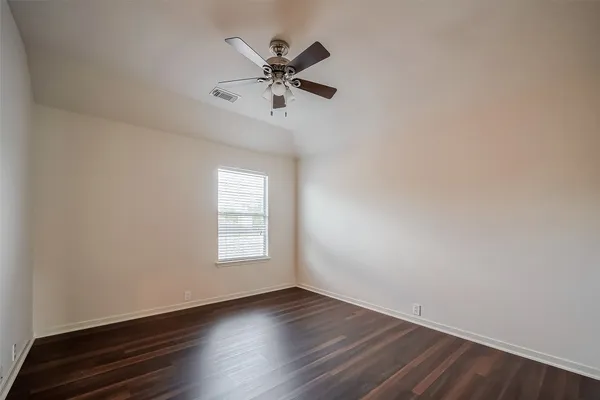 an empty room with wooden floor fan and windows