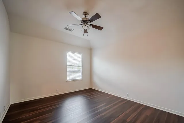 an empty room with wooden floor fan and windows