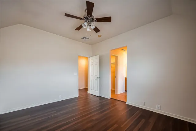 an empty room with wooden floor fan and windows