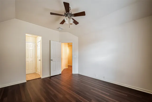 an empty room with wooden floor fan and windows