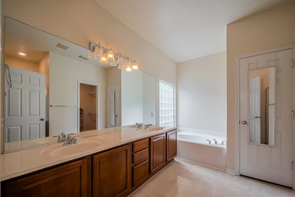 a bathroom with a double vanity sink a large mirror and a bathtub