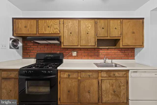 a kitchen with granite countertop a sink stove and cabinets