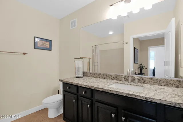 a bathroom with a granite countertop sink a toilet and a mirror