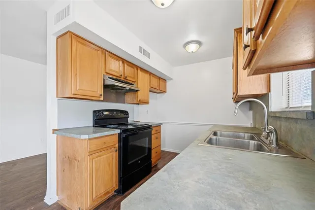 a kitchen with stainless steel appliances granite countertop a sink a stove and a wooden floors
