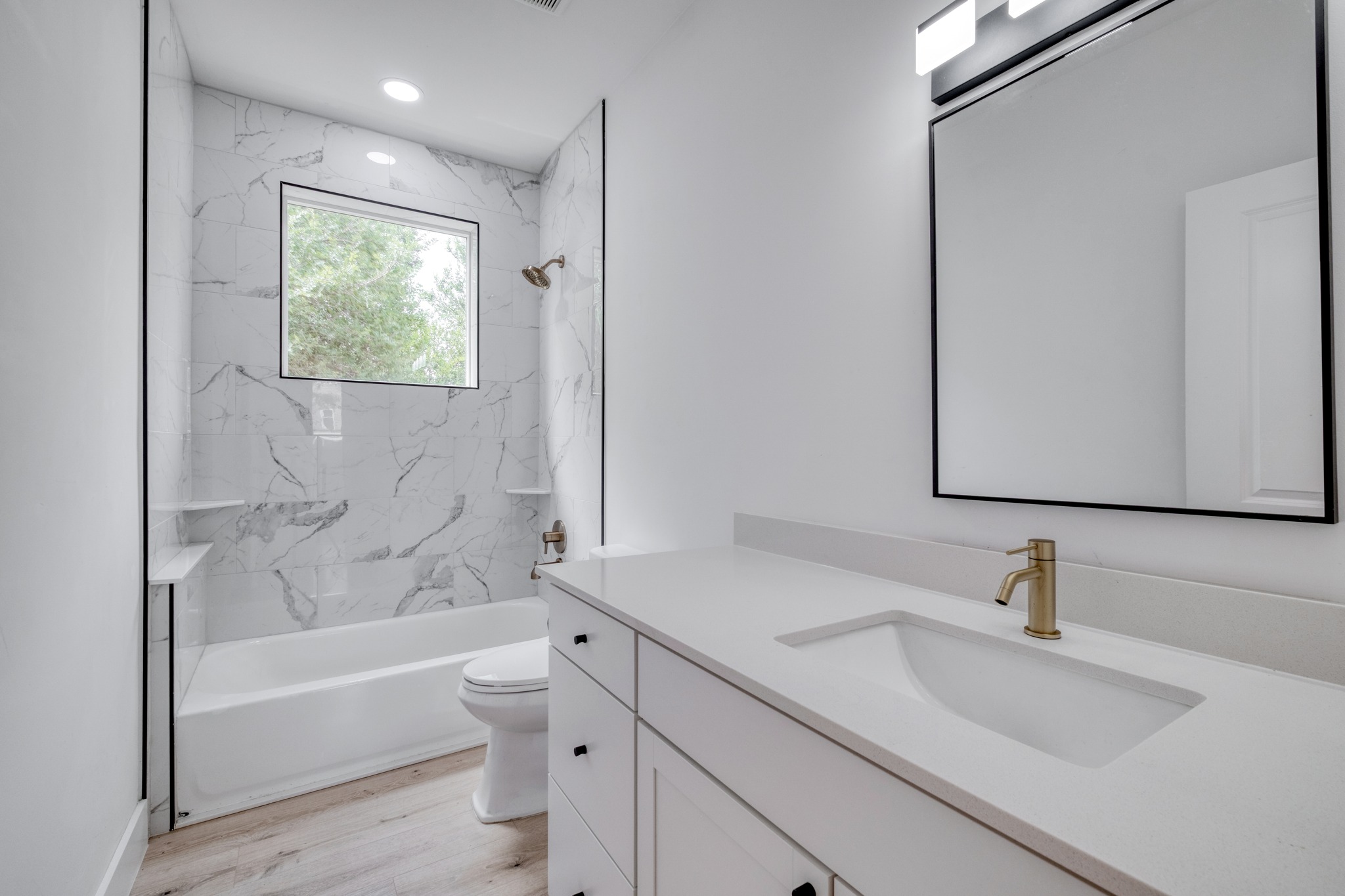 5211 Rob-Scott Street Austin, TX 78721 - Photo 12 of 24 A well-lit bathroom features a modern vanity and a sleek shower-tub combination with elegant tile work.