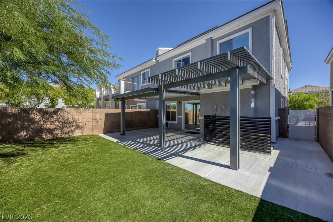 251 Integrity Ridge Drive Henderson, NV 89052 - Photo 25 of 32 A spacious backyard features concrete patio areas shaded by a modern grey pergola structure.