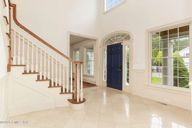 a view of a dining room and livingroom with furniture wooden floor a rug a flat screen tv a painting and a chandelier